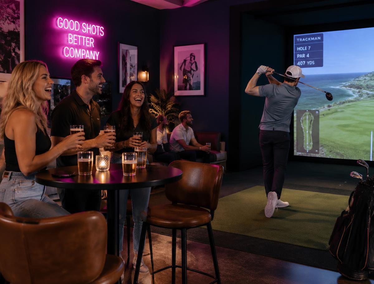 Des amis qui s'amusent au simulateur de golf Chez Putters
